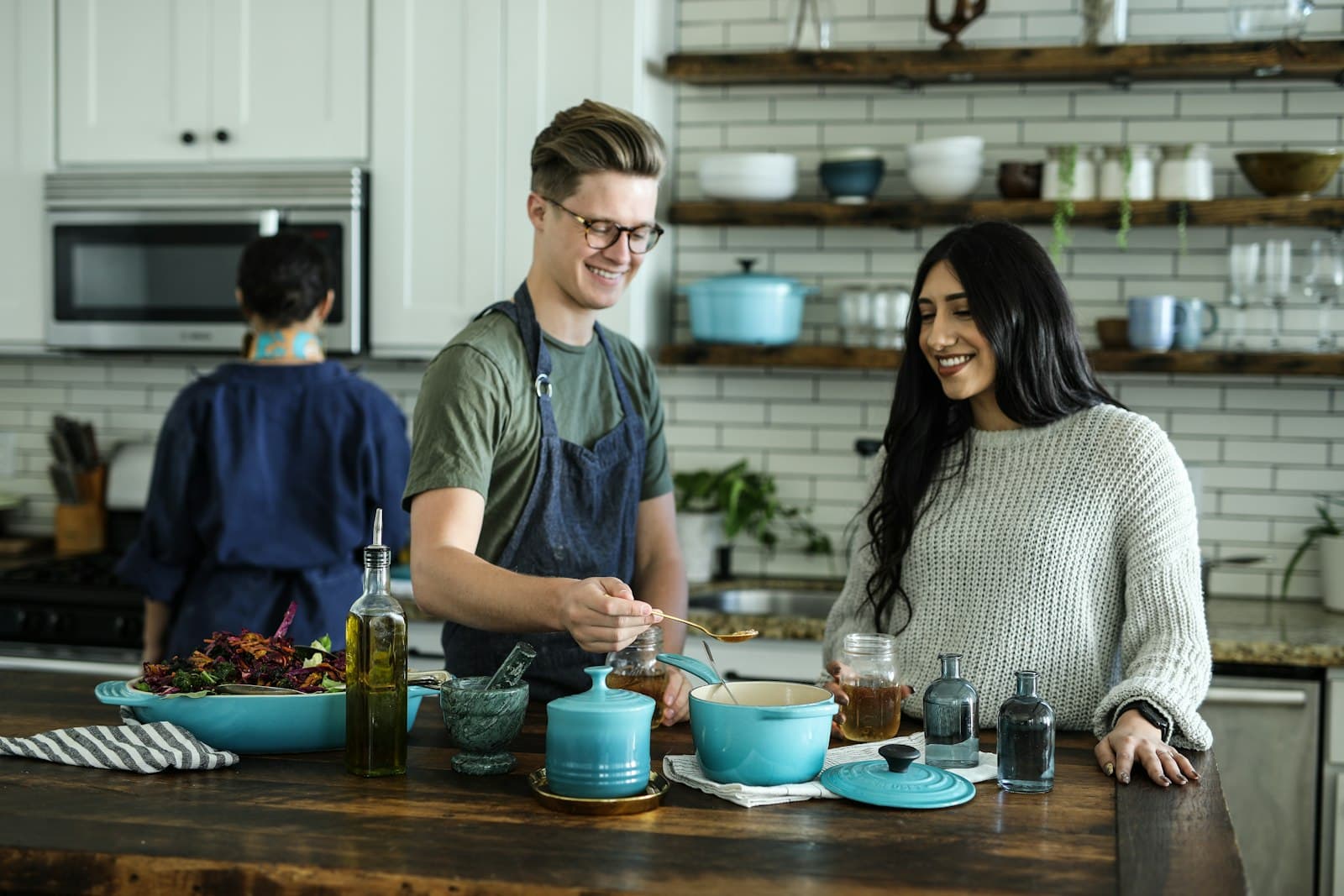 Tre persone che cucinano insieme in una cucina domestica, senza il prodotto pubblicizzato