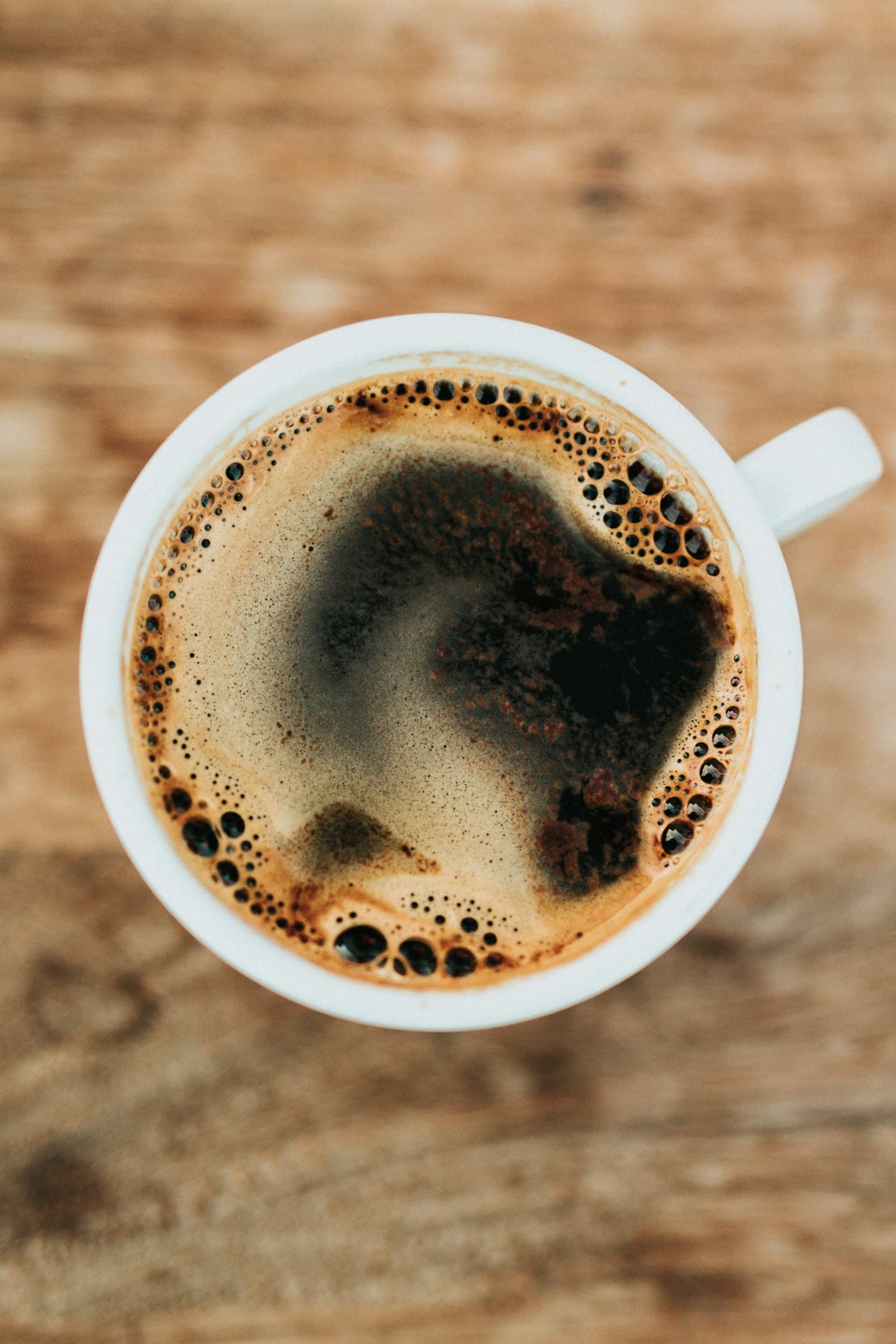 Tazza di caffè nero vista dall’alto su legno, illustrazione di uso quotidiano